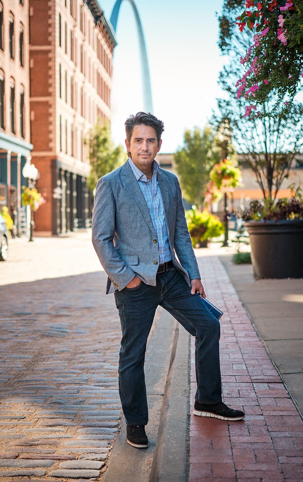 Walker Deibel standing on a downtown St. Louis brick street with the Gateway Arch in the background