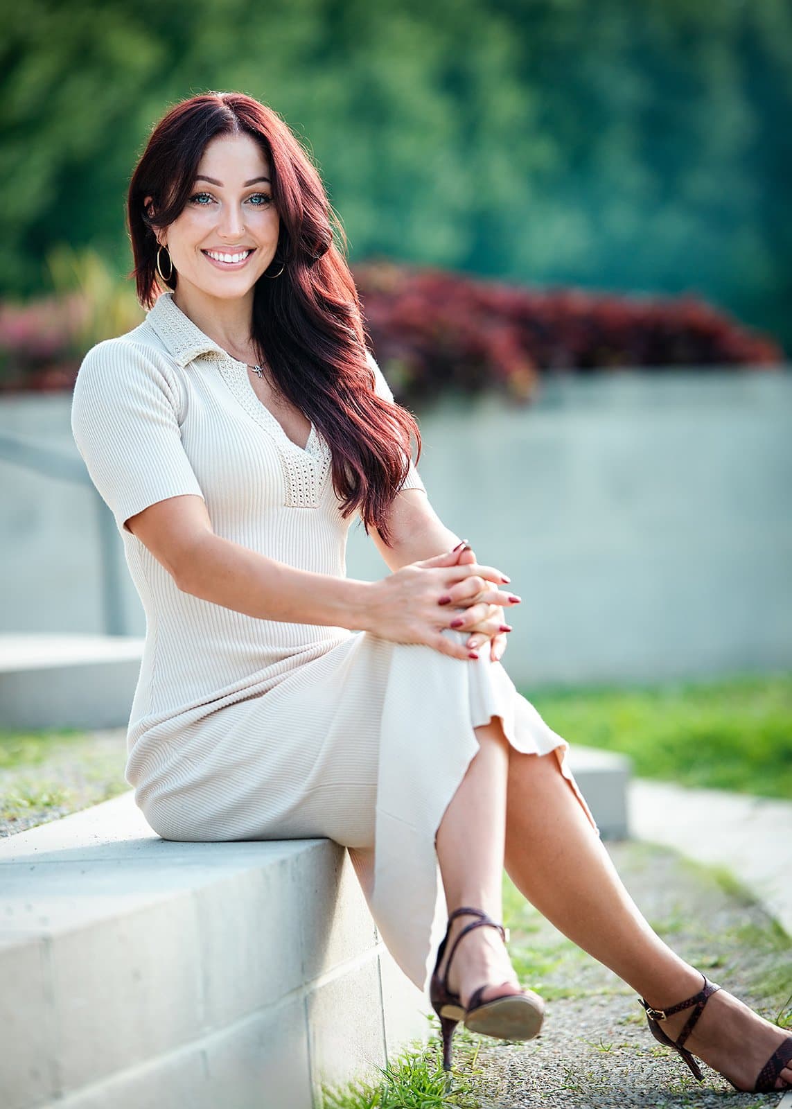 Natural light portrait of a smiling woman seated on a concrete ledge by Henry David Photography, the standard every Webster Groves headshot session is held to