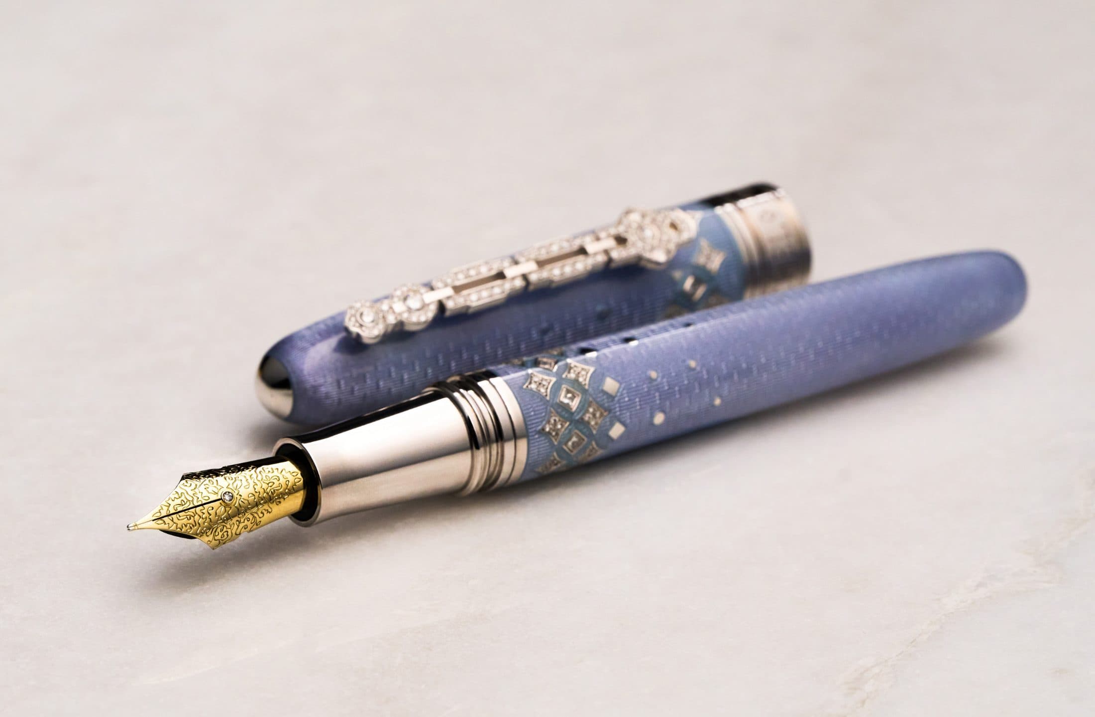Michel Perchin Majesty periwinkle fountain pen at rest, diamond-set clip, on Carrara marble