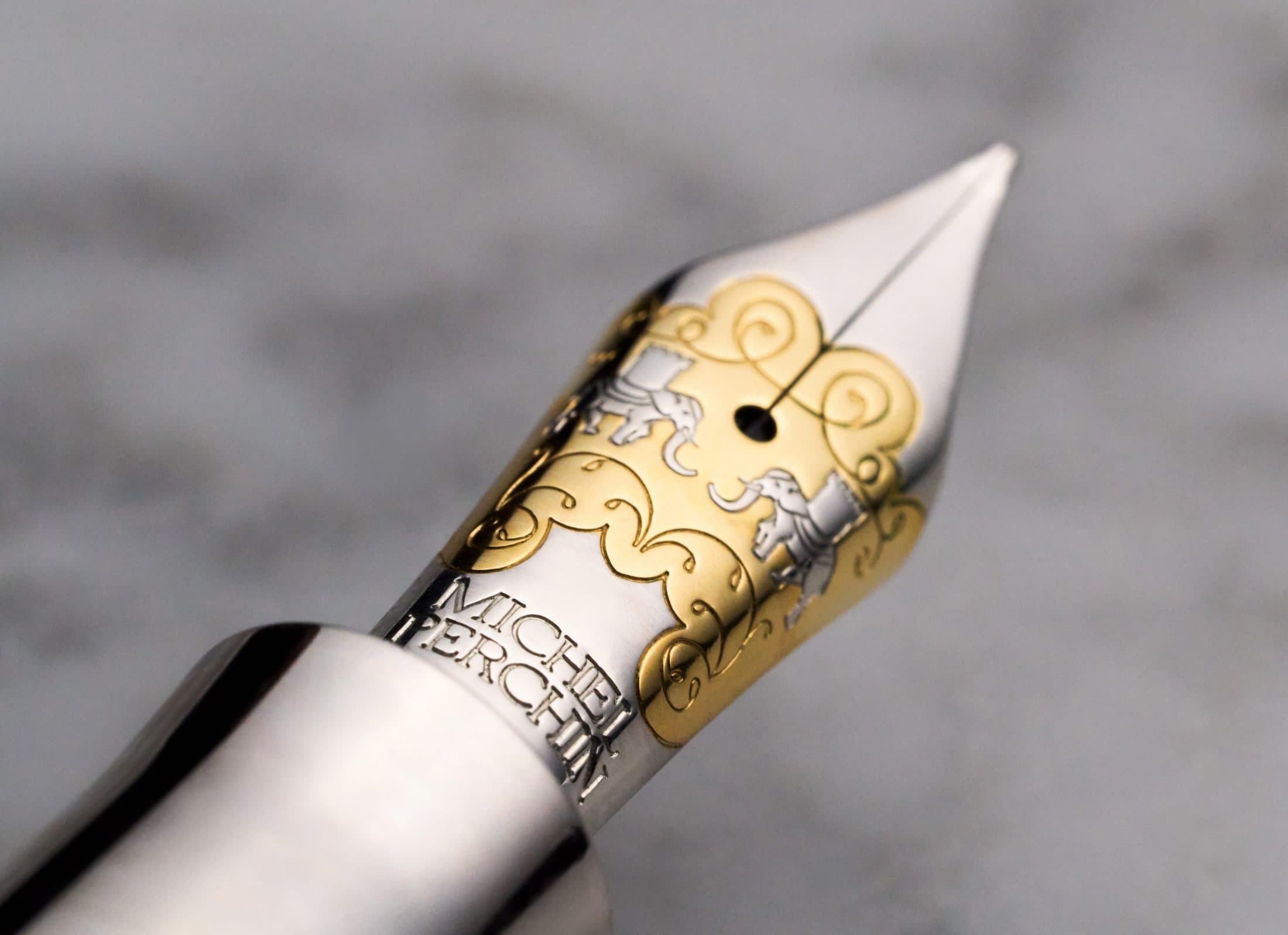 Macro of a Michel Perchin Majesty fountain pen nib with scrolled elephant engraving in gold and silver