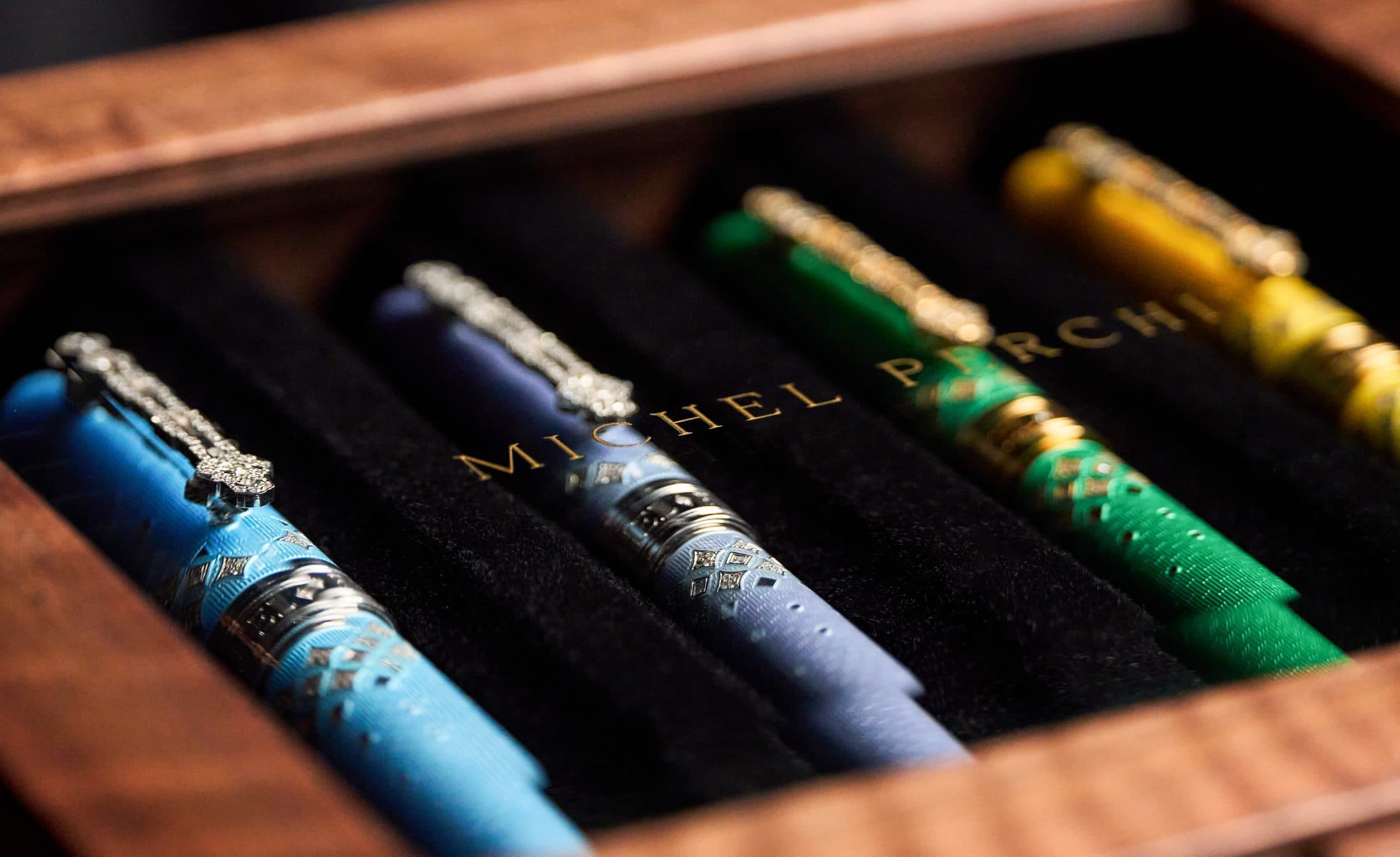 Michel Perchin Majesty fountain pens on dark velvet with warm gold light, cinematic macro by Henry David Photography