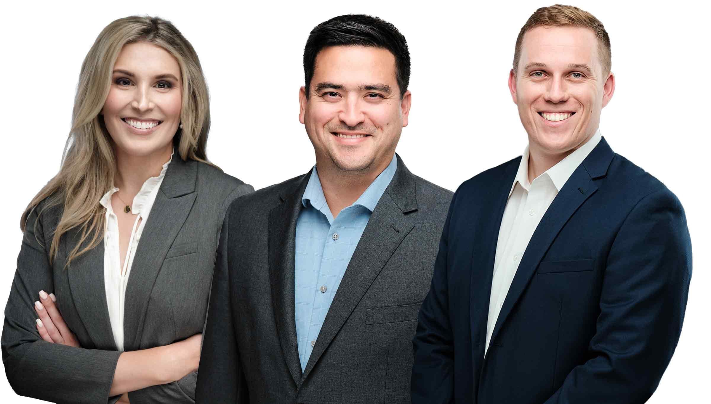 Three professionals (two women and one man) in tailored business attire smiling against a white seamless backdrop, examples of correct headshot wardrobe